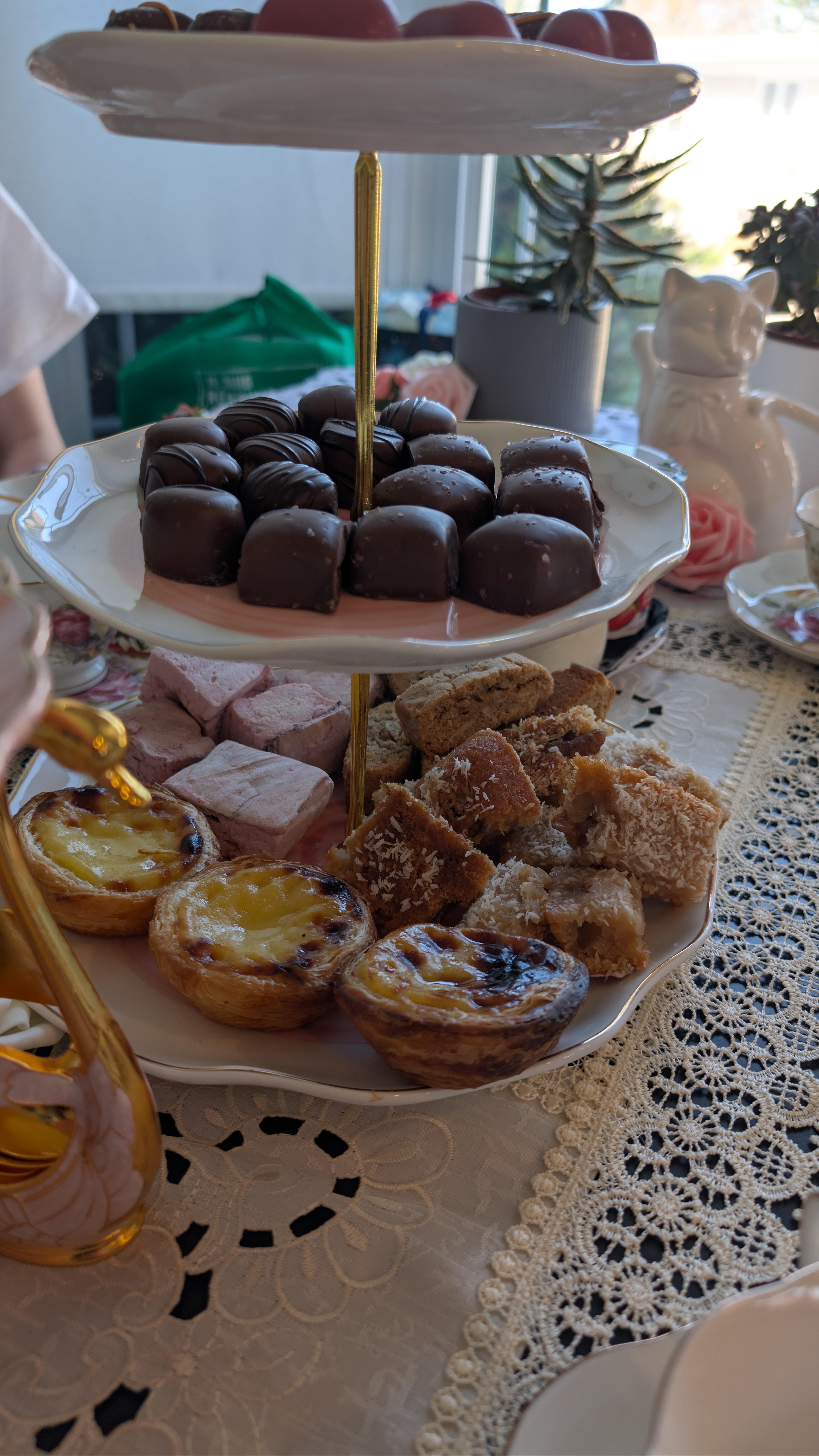 A stack plates filled with sweets. Chocolates, artisan marshmashllows, pasteis de nata, and some daqueen.
